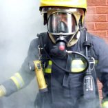 Fire-fighter-wearing-full-breathing-apparatus-and-protective-equipment-after-a-sprinkler-demonstration-exercise-large
